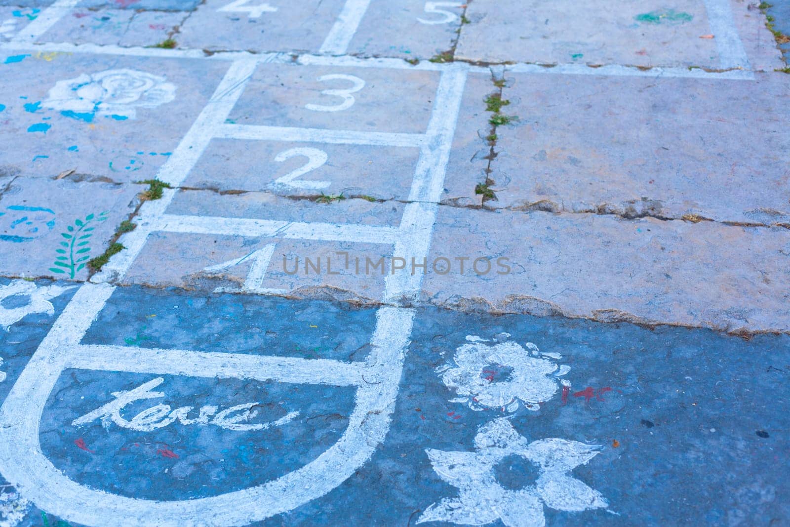 Hopscotch on an asphalt floor with chalk drawings of numbers and squares as an icon of youth innocence and children playing a fun jumping game at recess or after elementary school.
