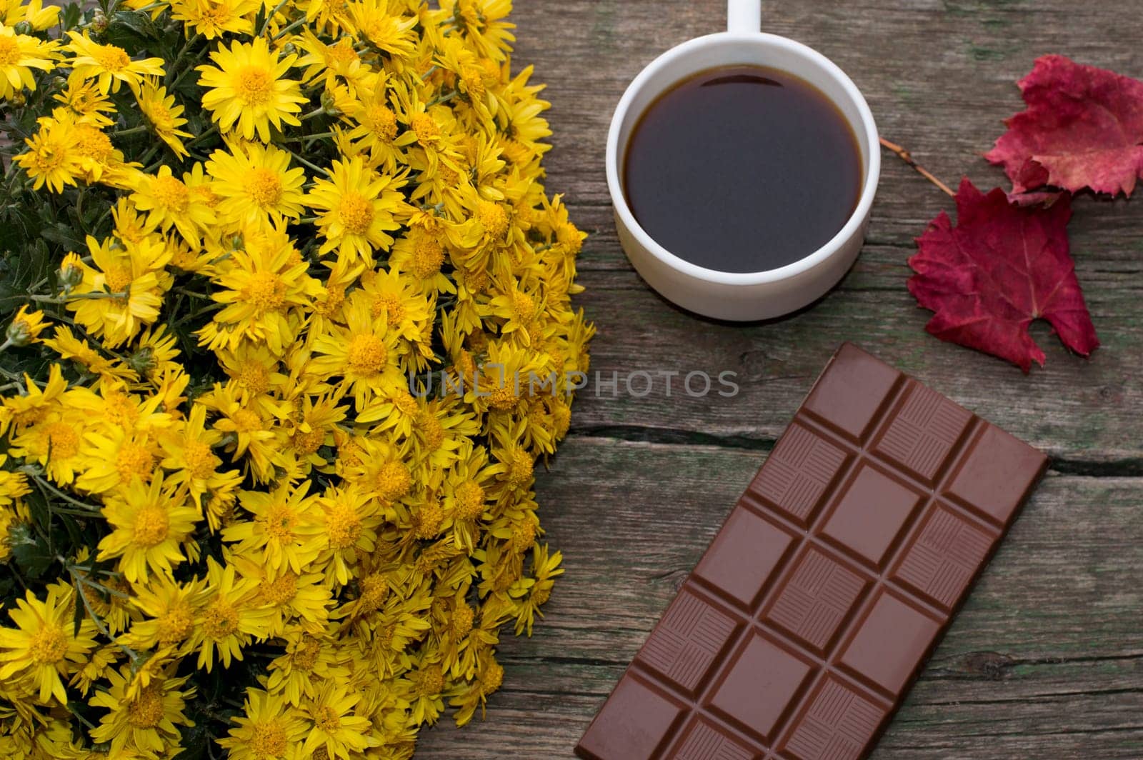 chocolate, red leaf, bouquet of yellow flowers and coffee, on a wooden table, a still life, a subject fall