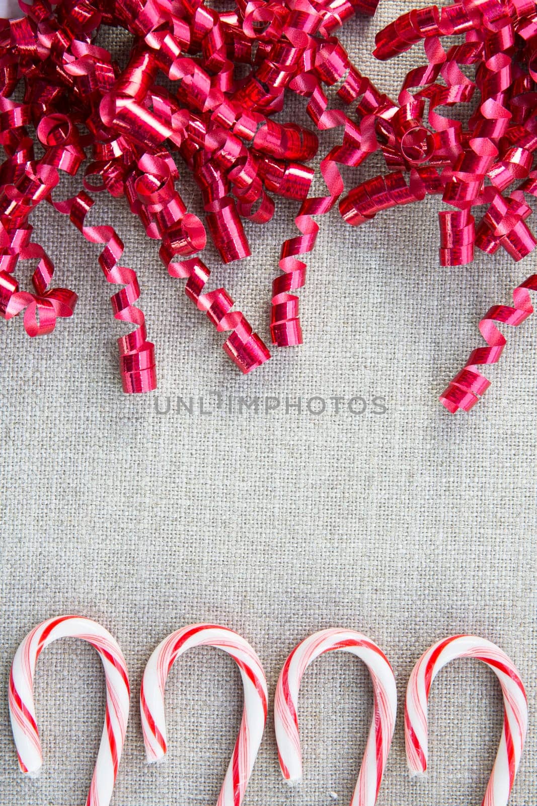 Candy canes and red curly ribbons with copy space in center.