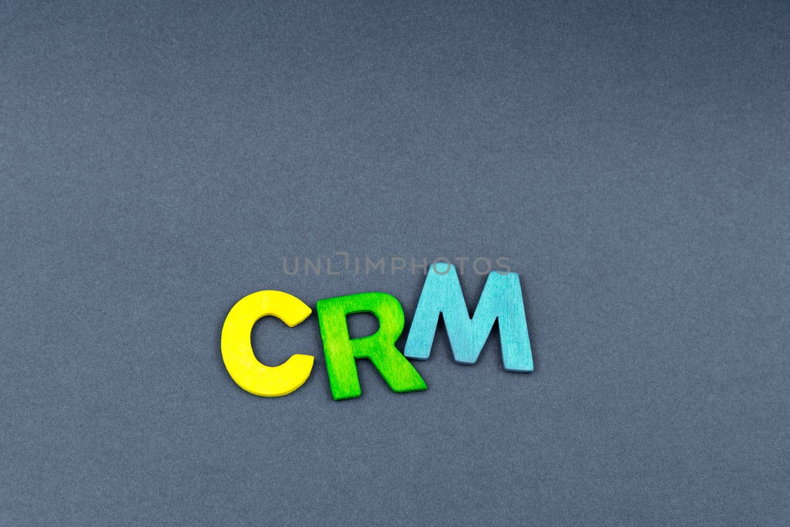 Business Abbreviation CRM as Customer Relationship Management created of wood letters on dark background, copy space available
