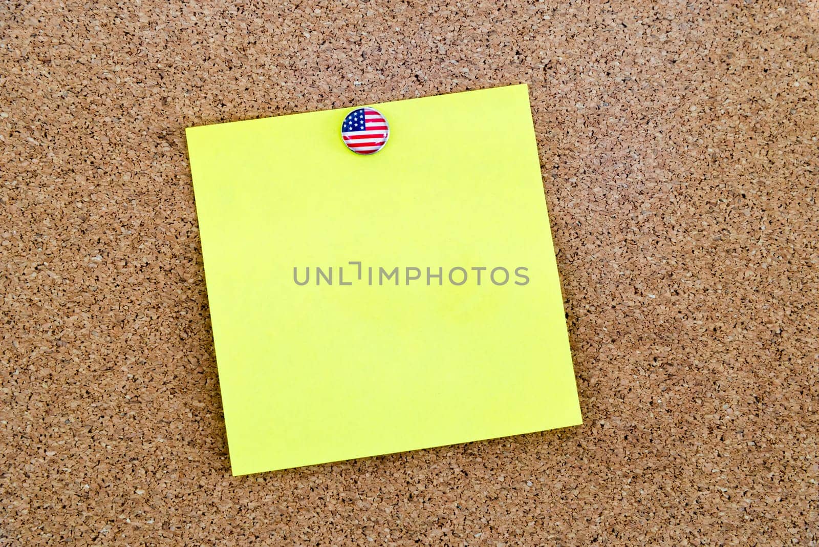 Blank yellow paper note pinned with United States flag thumbtack, copy space available