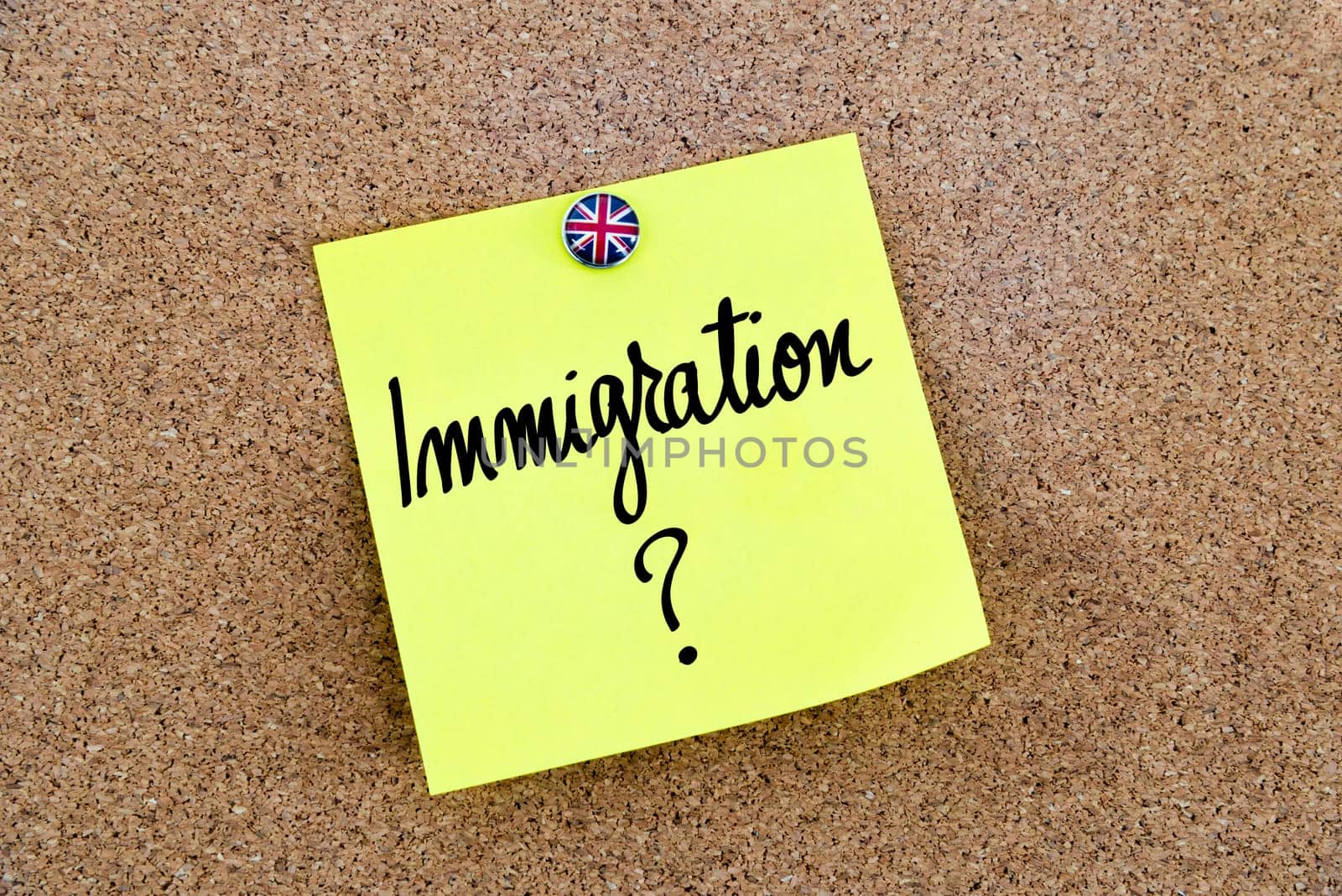 Yellow paper note pinned on cork board with Great Britain flag thumbtack, written text IMMIGRATION, United Kingdom exit from European Union concept