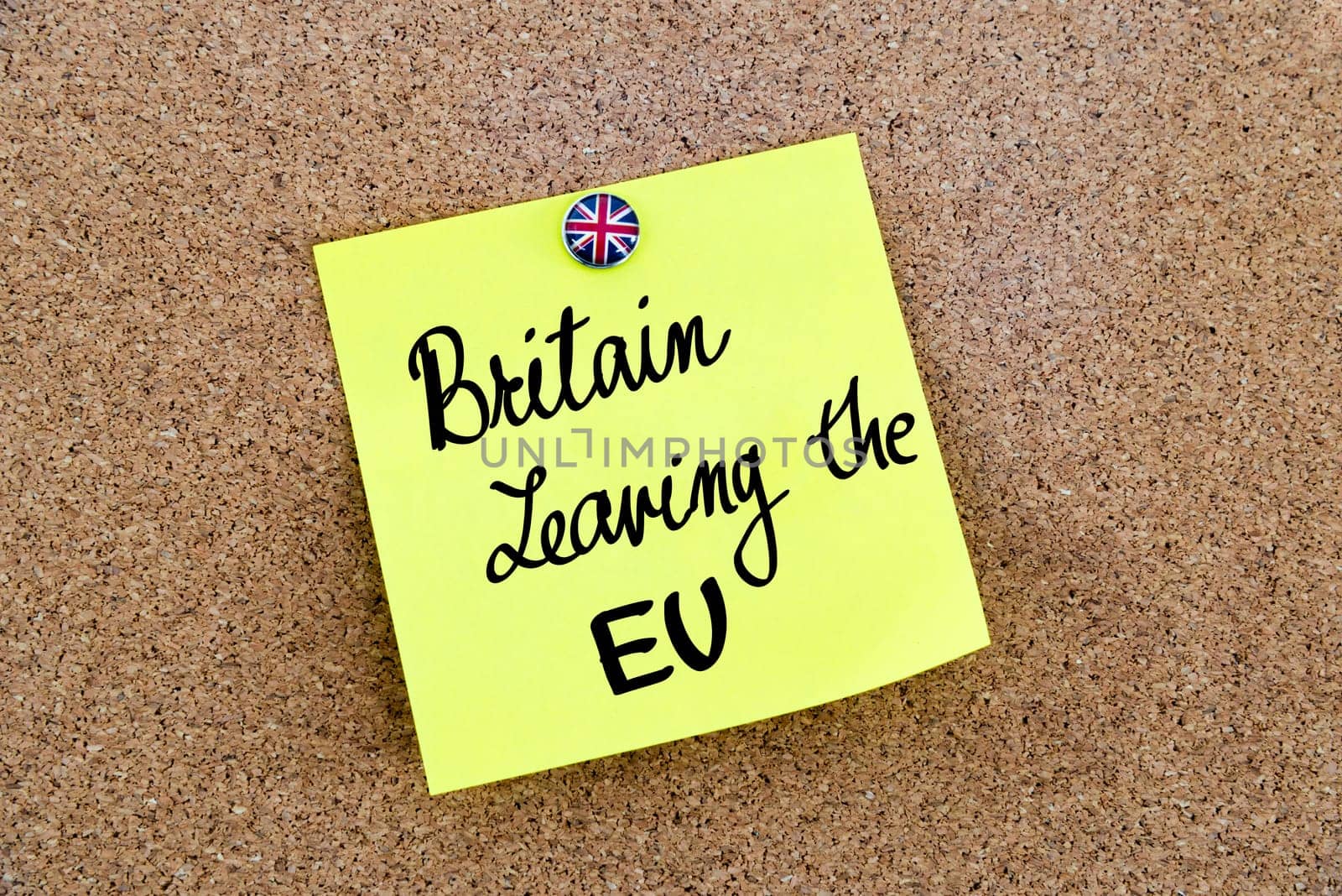 Yellow paper note pinned on cork board with Great Britain flag thumbtack, written text BRITAIN LEAVING THE EU, United Kingdom exit from European Union