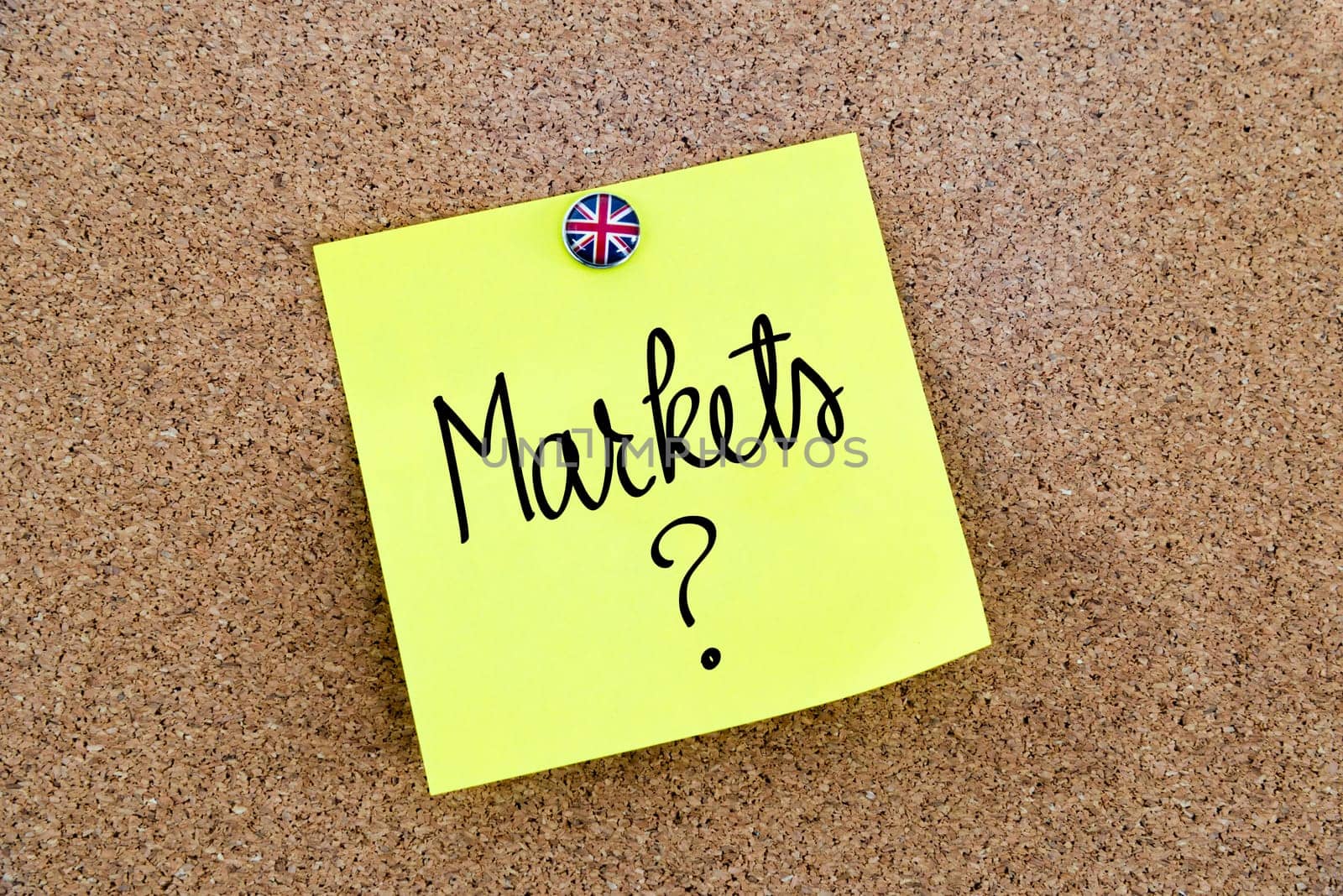 Yellow paper note pinned on cork board with Great Britain flag thumbtack, written text MARKETS ?, United Kingdom exit from European Union concept
