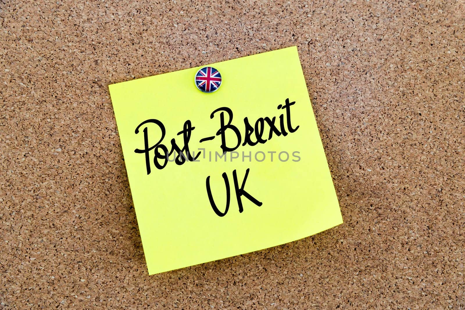 Yellow paper note pinned on cork board with Great Britain flag thumbtack, written text POST-BREXIT UK, United Kingdom exit from European Union