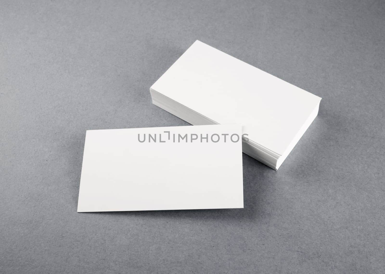 Photo of blank business cards with soft shadows on gray background. Mock-up for branding identity. Studio shot.