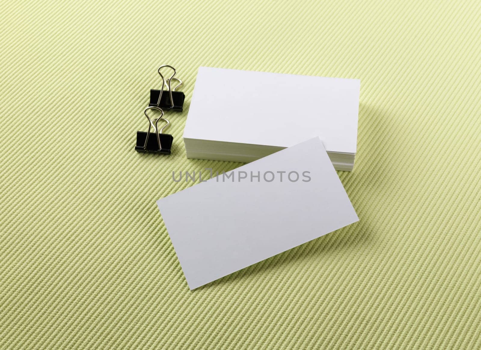 Stack of blank business cards on a green background. Template for branding identity.