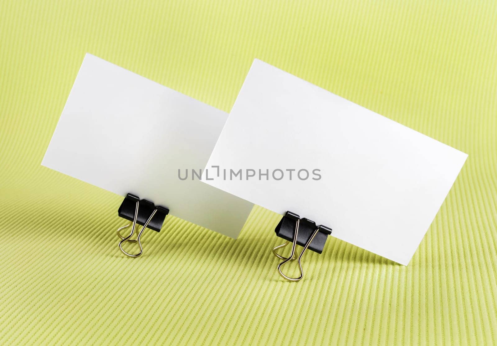 Photo of two blank business card with soft shadows on green background. Template for branding identity.