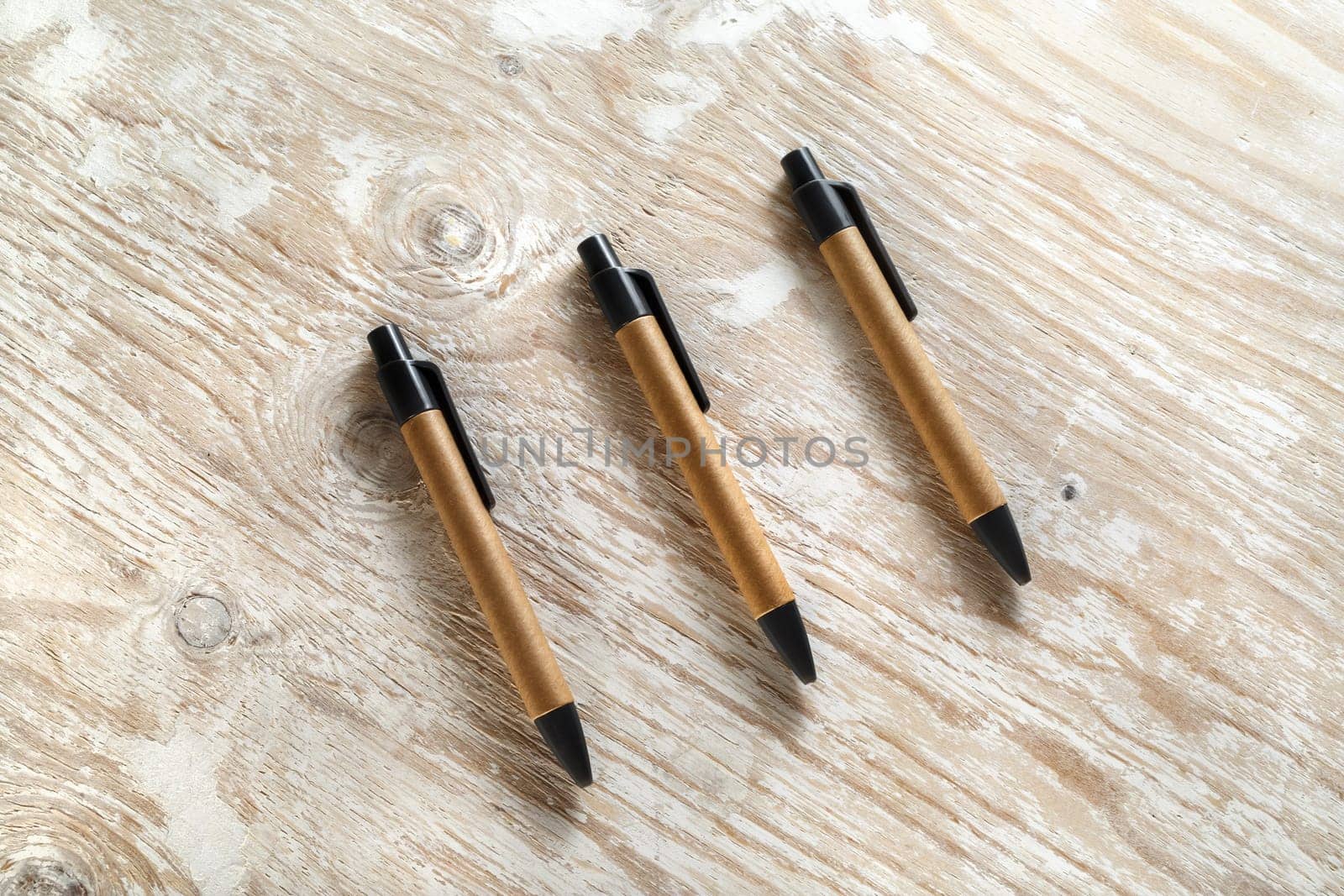 Three mechanical ballpoint pens on the wooden background. Template for design presentations and portfolios. Top view.