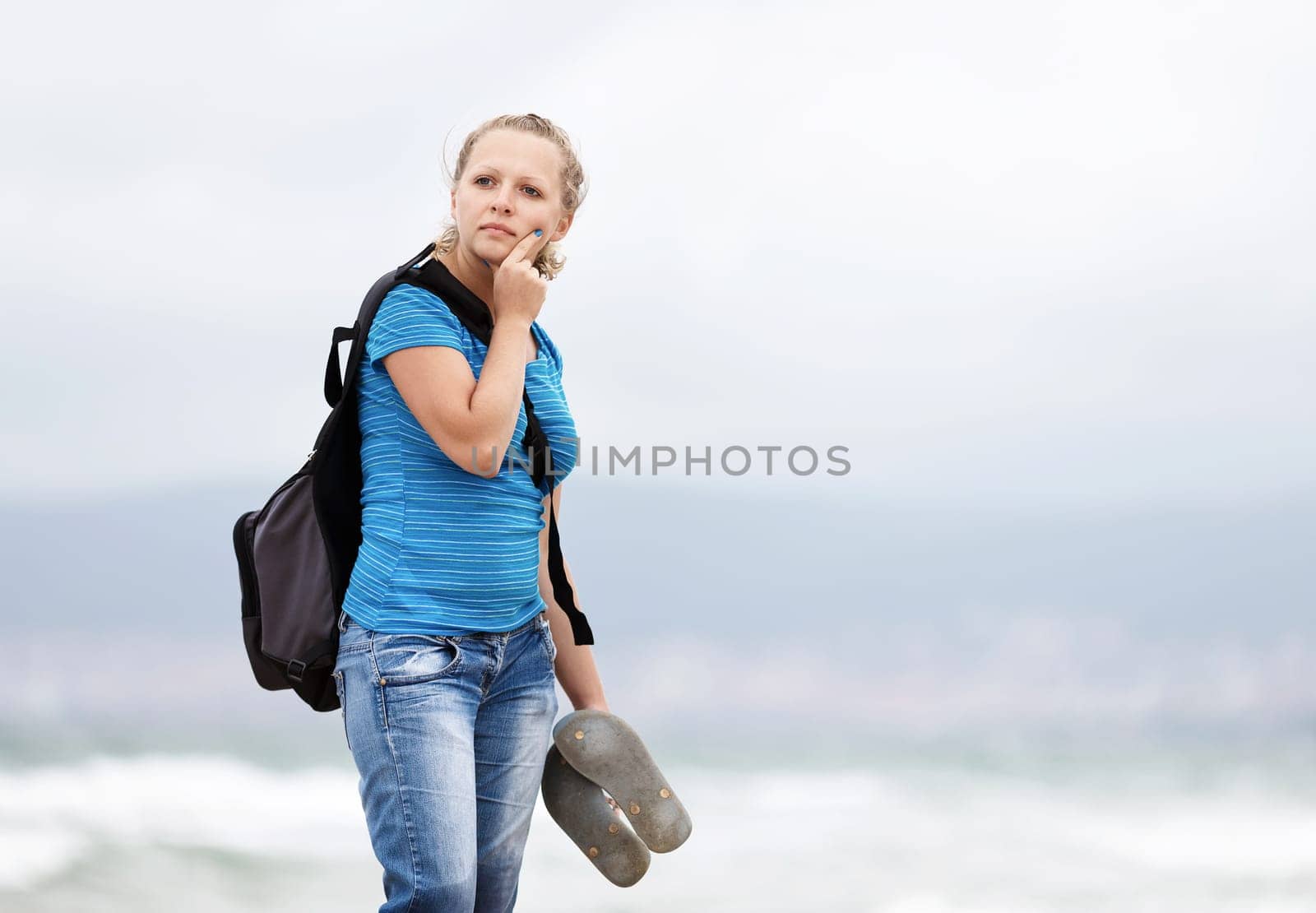 Pretty young blonde woman with a backpack standing outdoors. Girl with backpack. Selective focus on model.