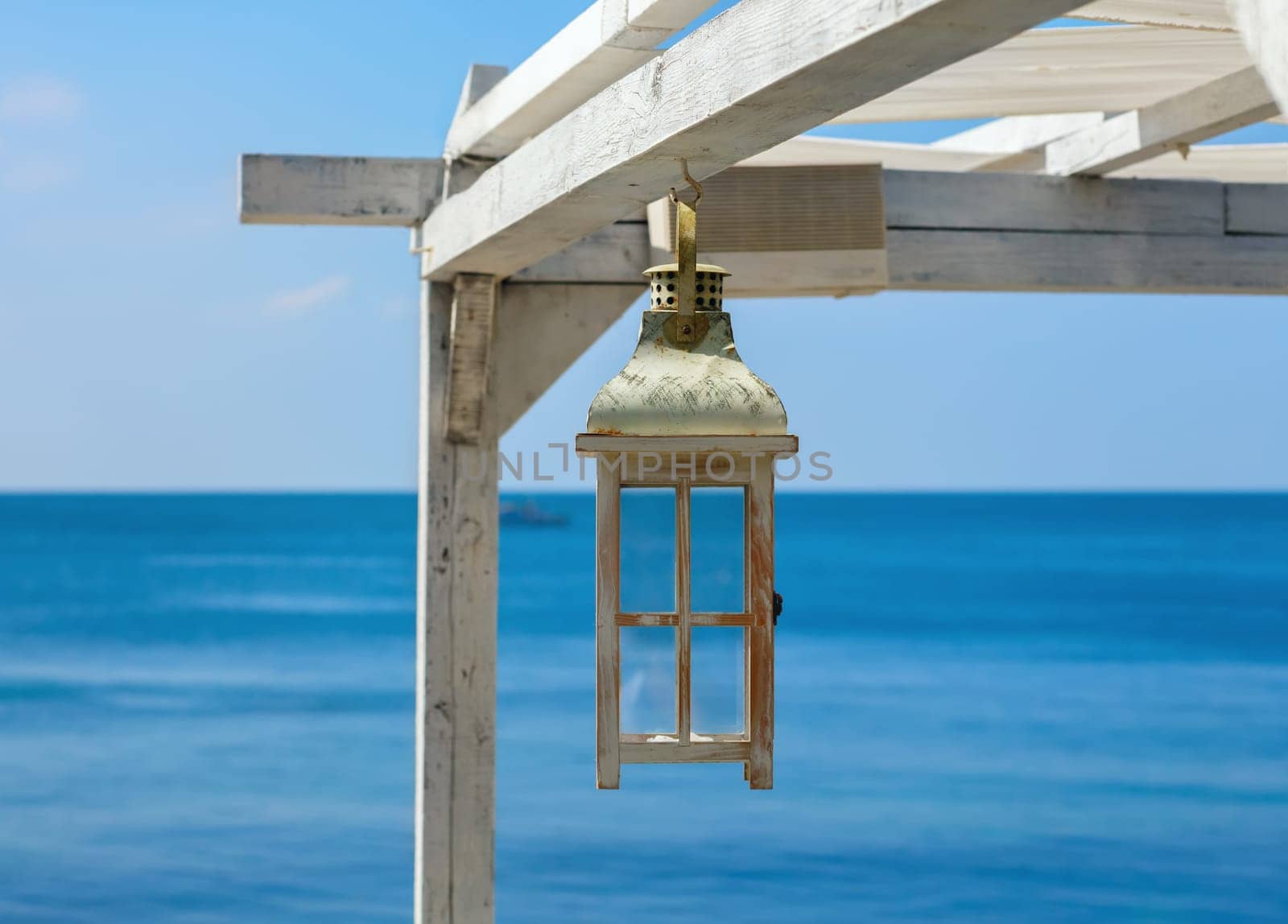 Vintage white lantern. Painted Wooden lantern on a background of the sea and blue sky. Selective focus on the lantern.