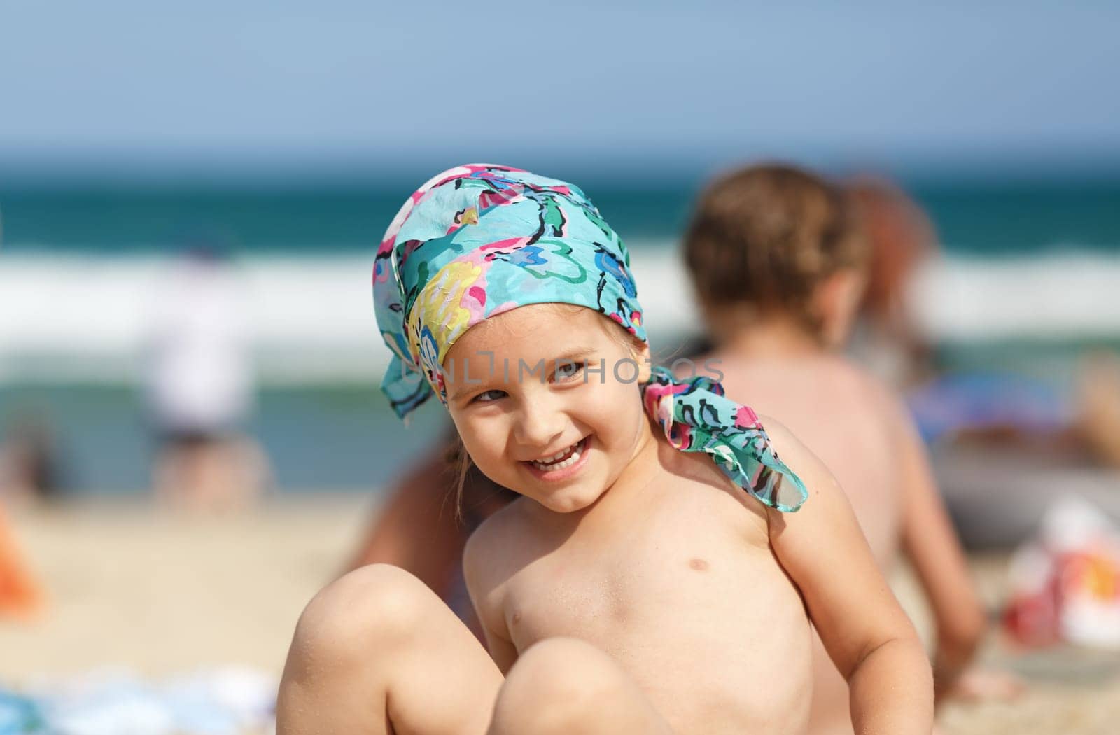 Laughing little girl on the beach. Focus on model. Shallow depth of field.