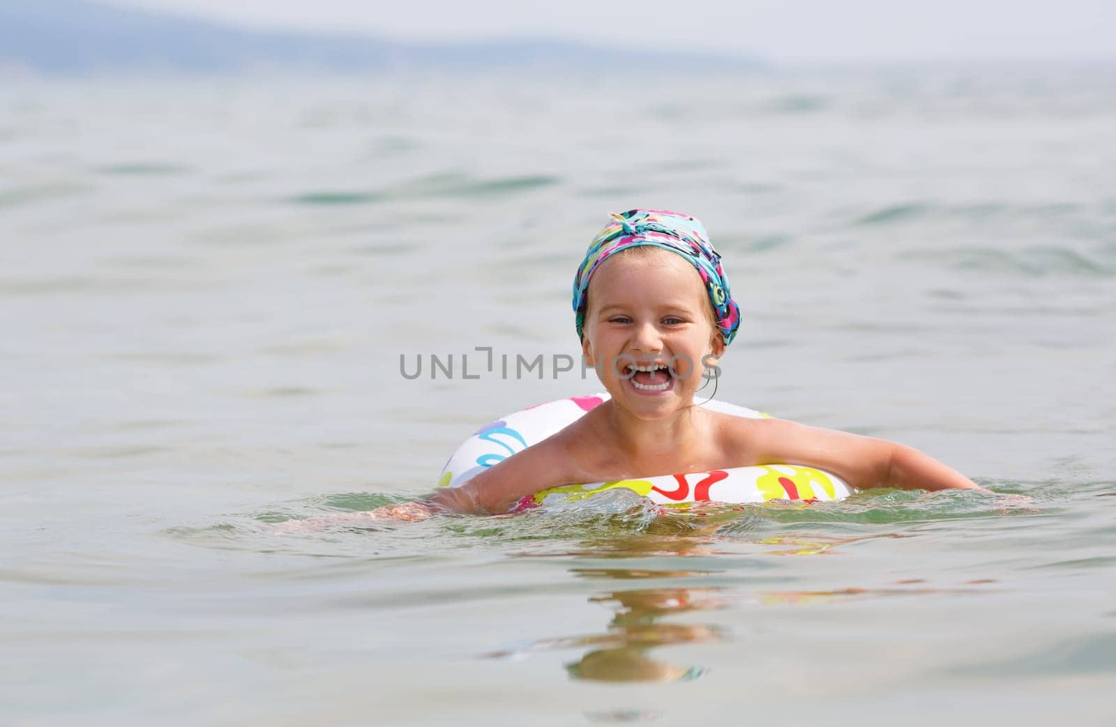 Happy child swims in the sea on inflatable ring on a clear sunny day. Shallow depth of field. Focus on model.