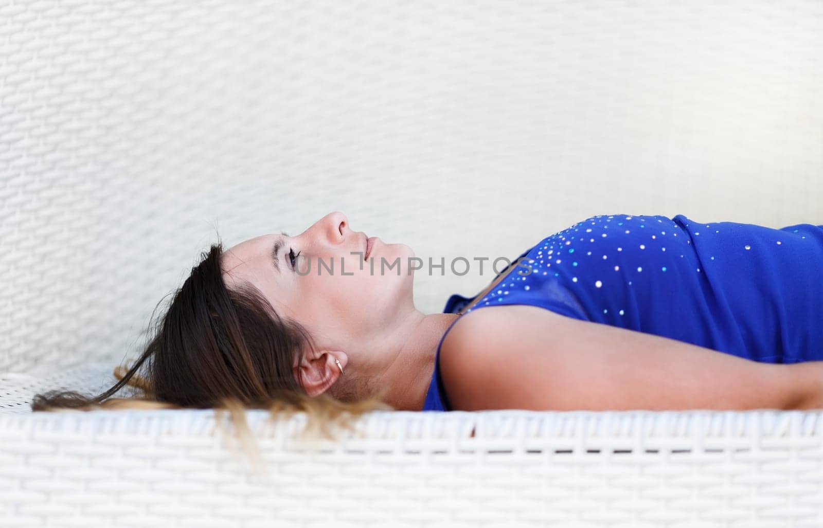Close-up of a beautiful young woman in a blue shirt relaxes lying and looking up. Shallow depth of field. Selective focus on the model's face.