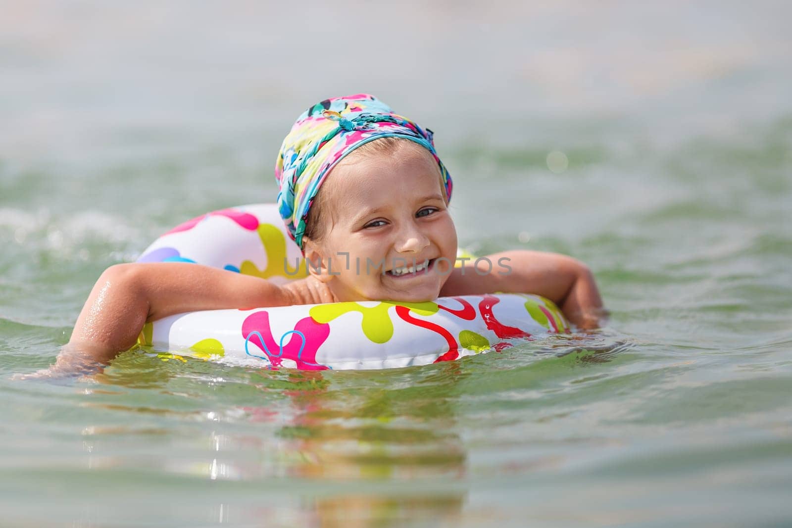 Happy child swims in the sea on inflatable ring on a clear sunny day. Shallow depth of field. Selective focus on the model's face.