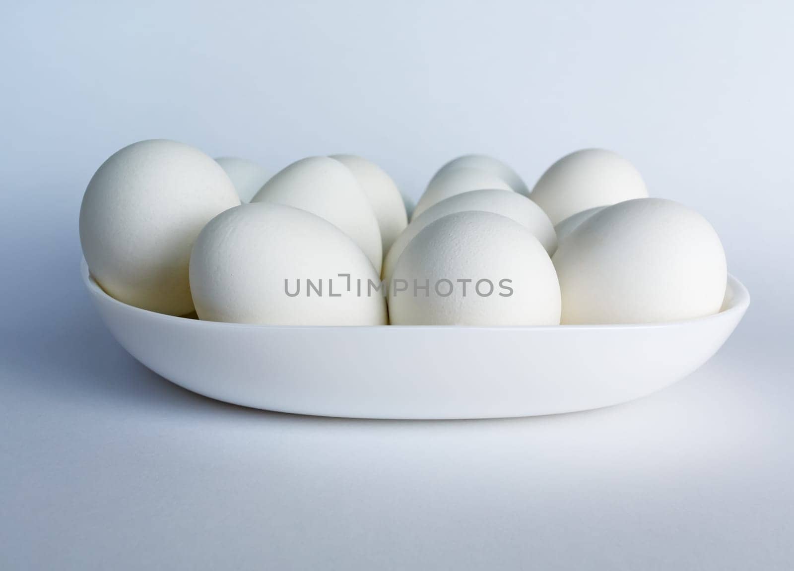 White eggs on a white plate on a light background