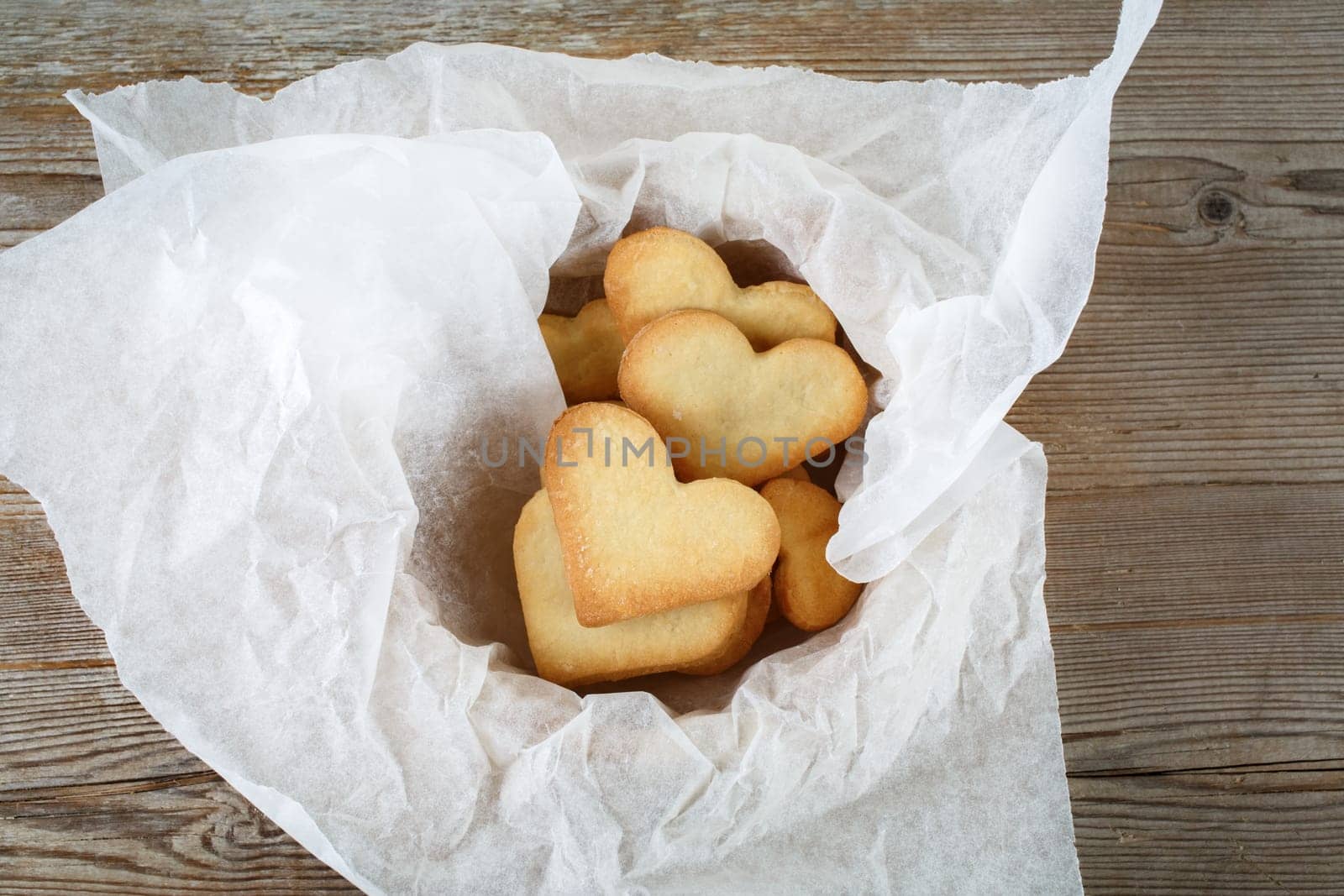 Heart shaped cookies in a paper wrapper on a wooden background. Top view.