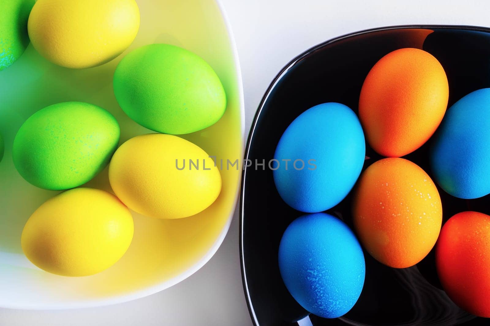 Bright colored Easter eggs in a black and white dishes.