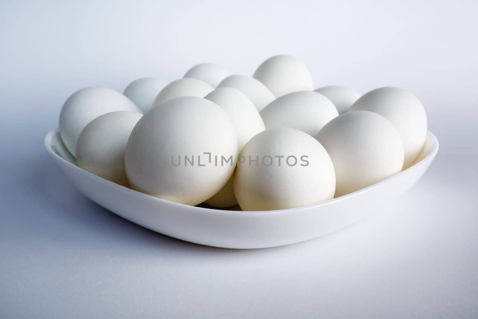 Photo of white eggs on a white square dish on a light background.