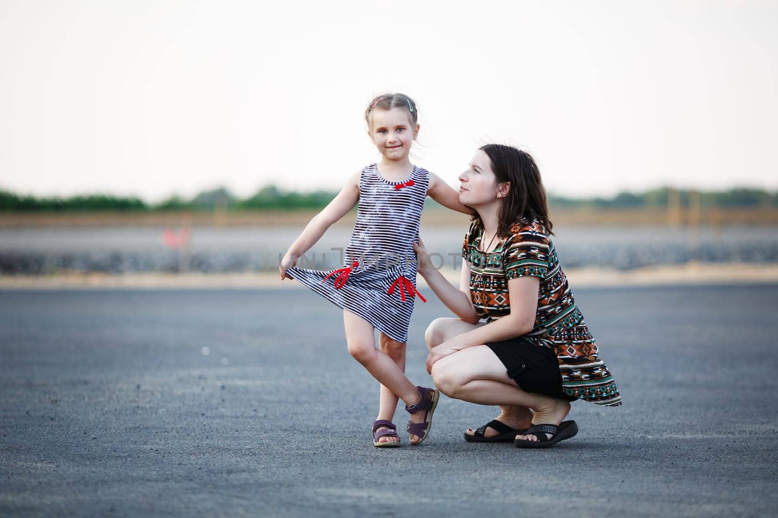 Happy family. Mother and little daughter posing for a photo on a background of asphalt road. Shallow depth of field. Selective focus.