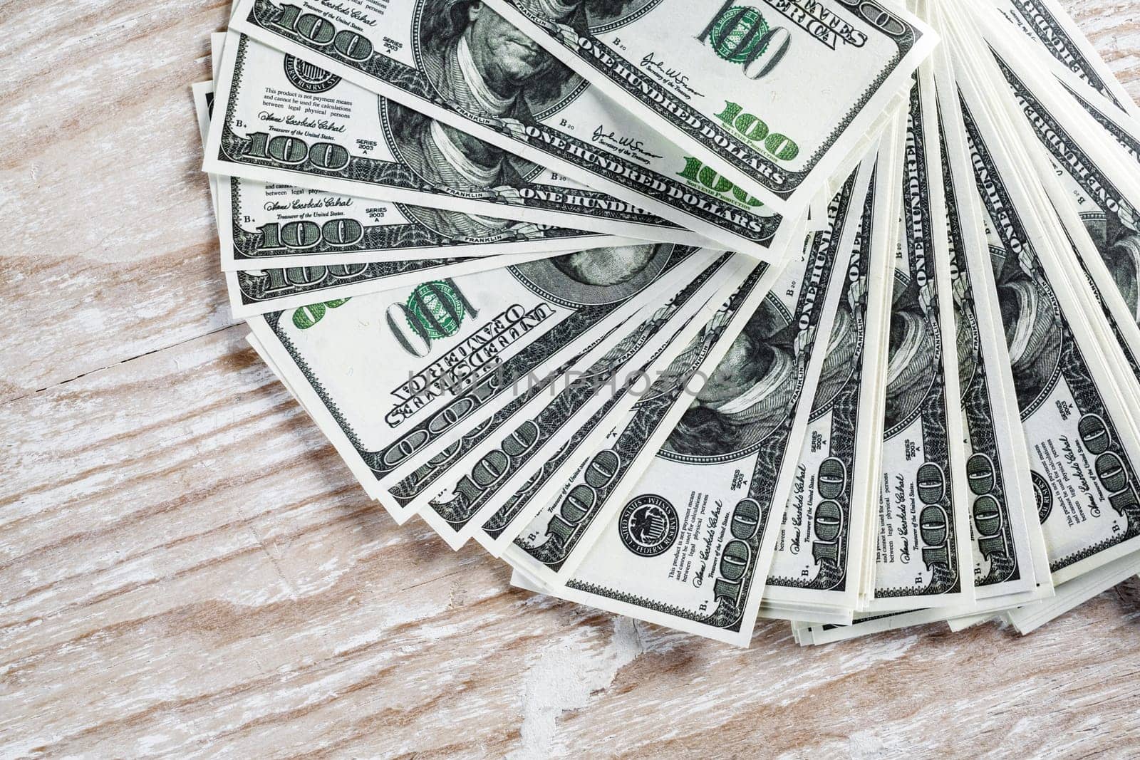 Many one hundred dollar bills on light wooden background. Pile of money.