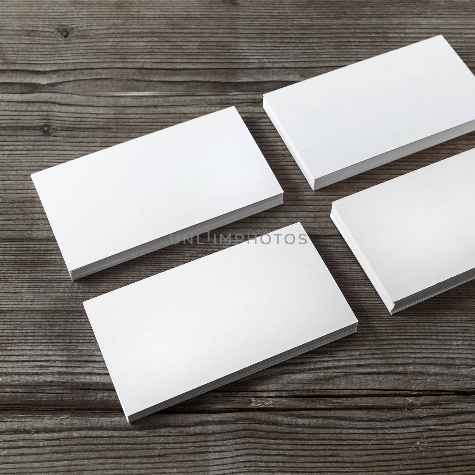 Set of blank white business cards on a dark wooden background. Template for branding identity. Shallow depth of field.