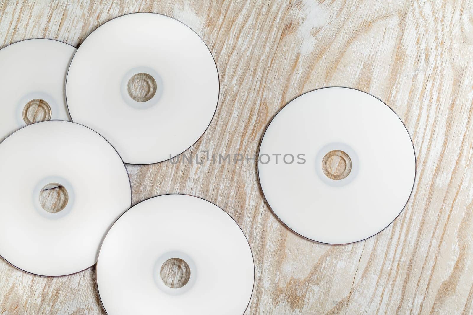 Blank printable CD and DVD on light wooden background. Top view.