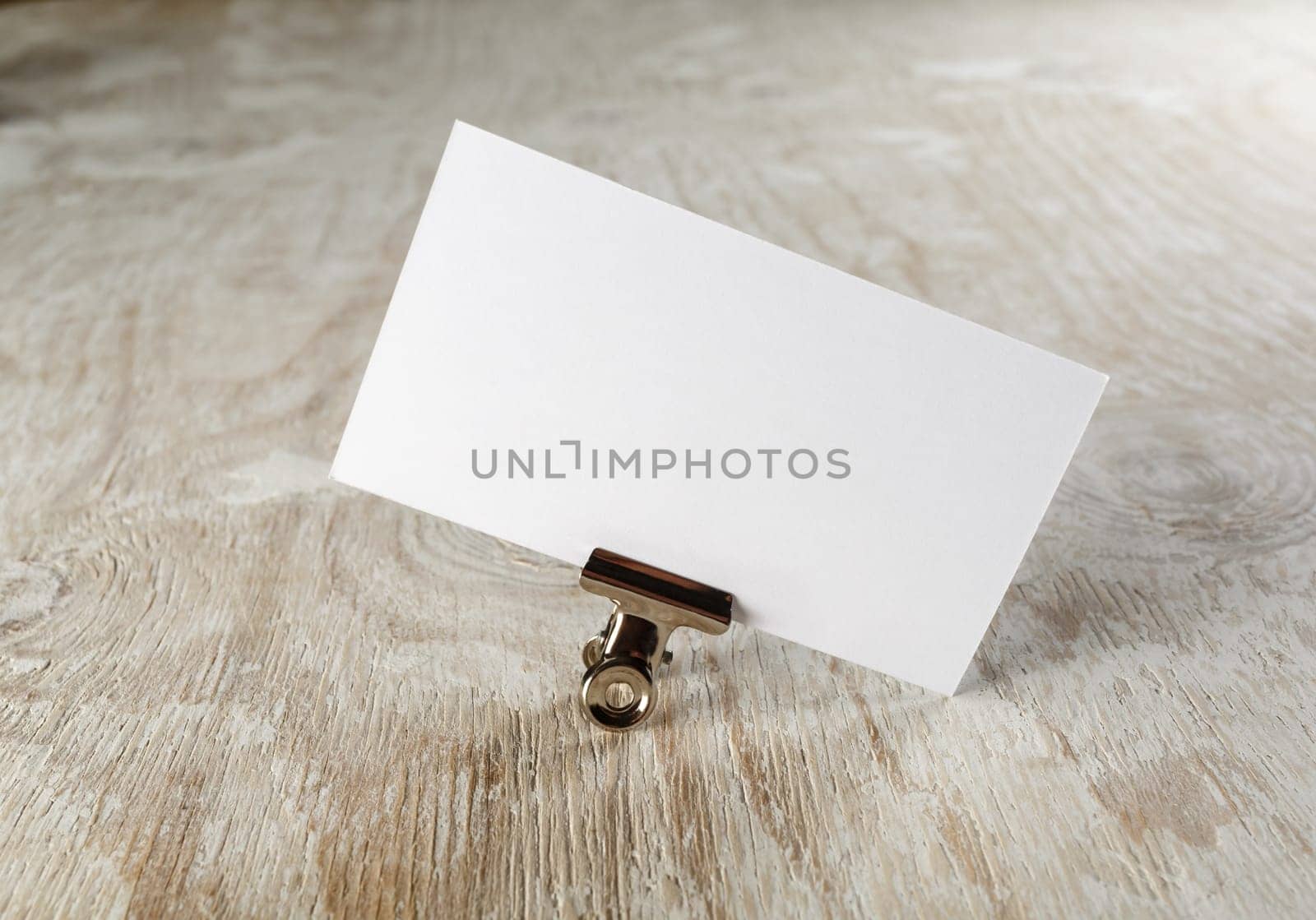 Photo of blank business card with soft shadow on light wooden background. Mock-up for branding identity.
