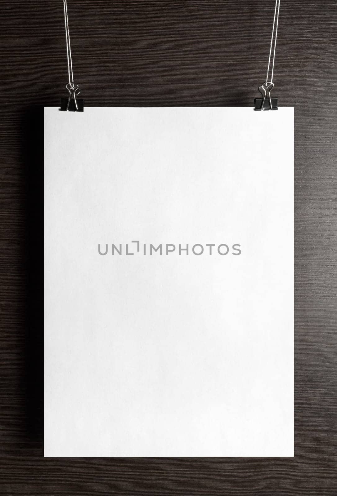 Blank white paper poster hanging on a wooden background. Vertical shot.