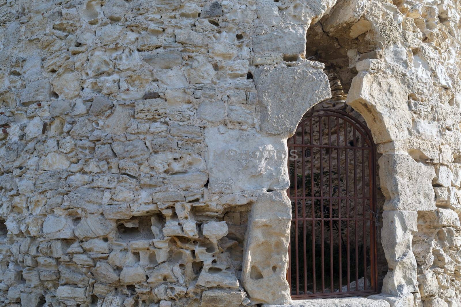 A large fragment of the old retro stone wall with rusty metal grate.
