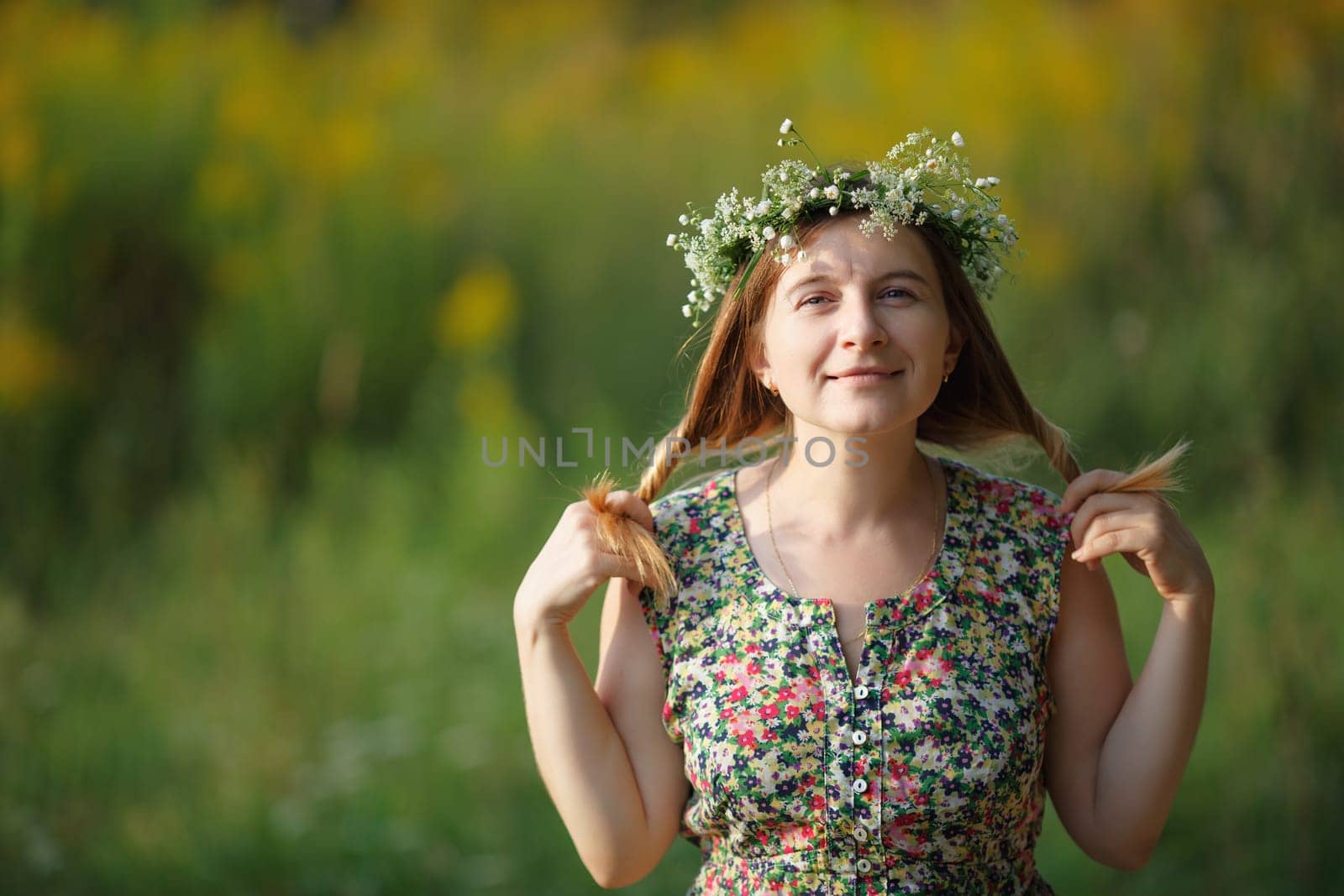 Smiling girl with a wreath keeps his hair. Sunset light. Space for text. Shallow depth of field. Focus on eyes.