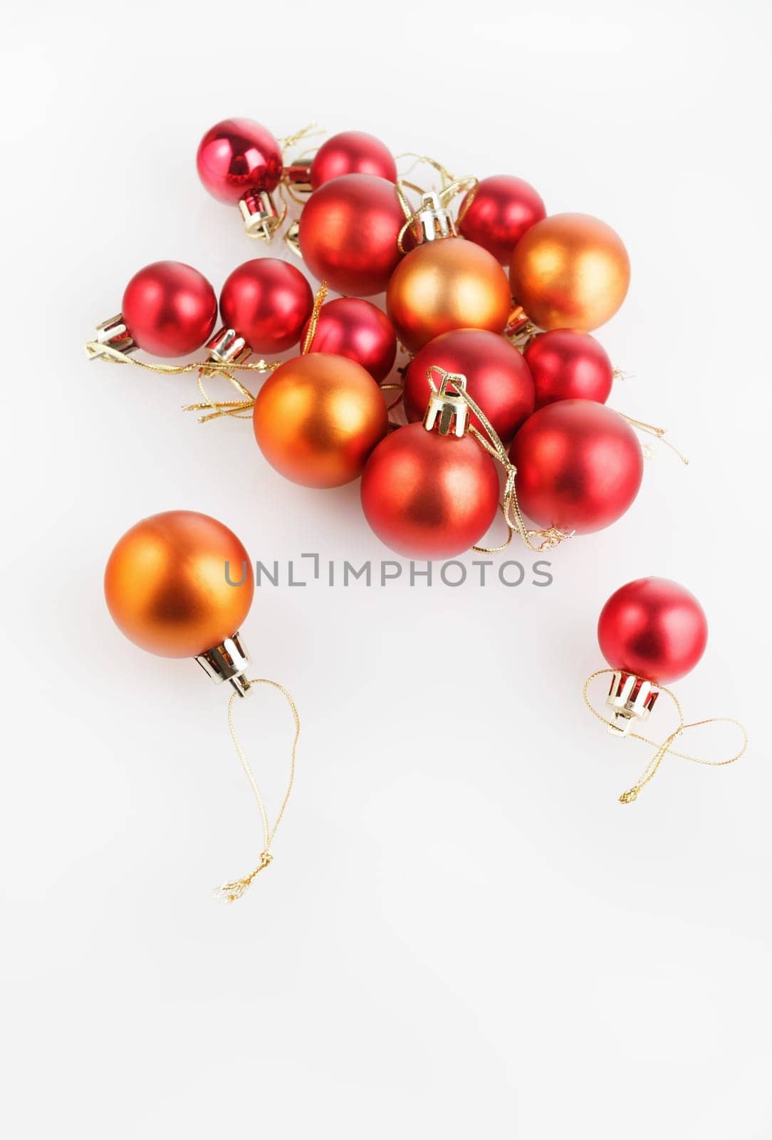 Bright shiny red and orange Christmas balls on a light background. Shallow depth of field. Selective focus. Space for text. Vertical shot.