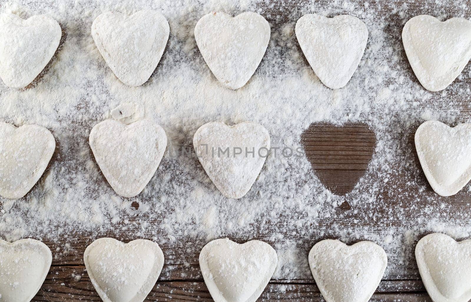 Heart-shaped ravioli sprinkled with flour on a wooden tabletop. Cooking dumplings. Top view
