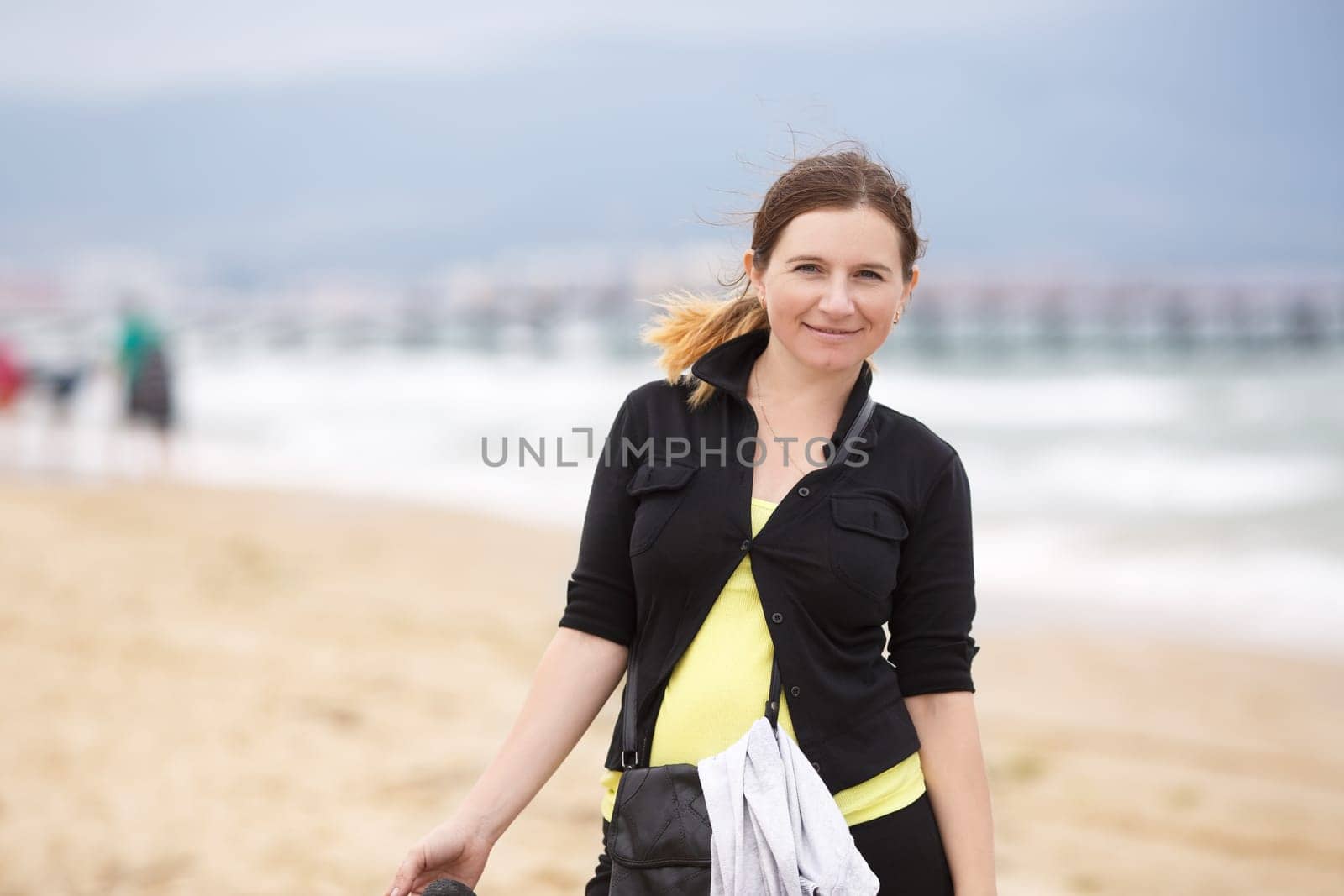 Smiling woman in a black blouse with a blurred background beach and sea.  Shallow depth of field. Focus on model.