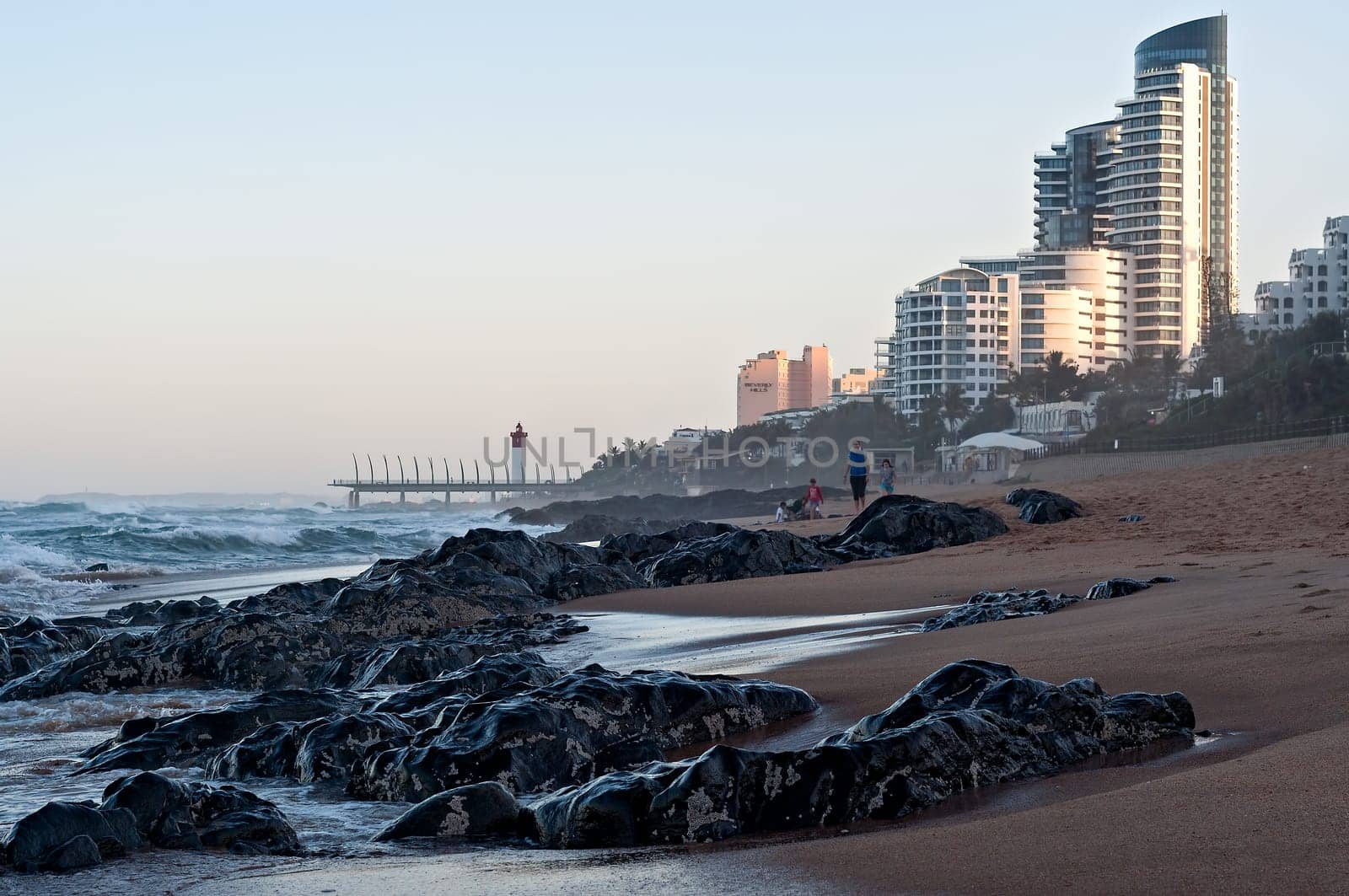 DURBAN, SOUTH AFRICA - JULY 11, 2016: People on the beach at Umhlanga Rocks, with the Millennium Pier and lighthouse in the background.