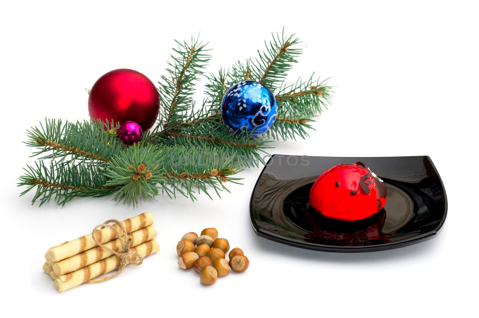 black plate with red cake, a fir-tree branch, cookies and nutlets, the subject Christmas and New Year