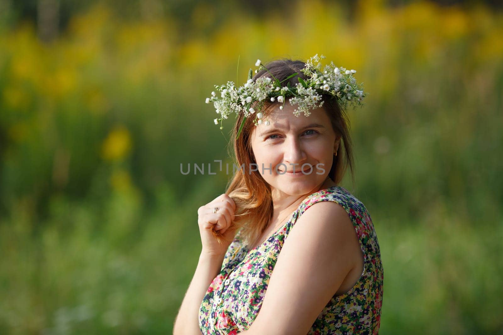 Pretty young woman with wreath on her head smiling and looking at the camera. Sunset light. Shallow depth of field. Focus on model.