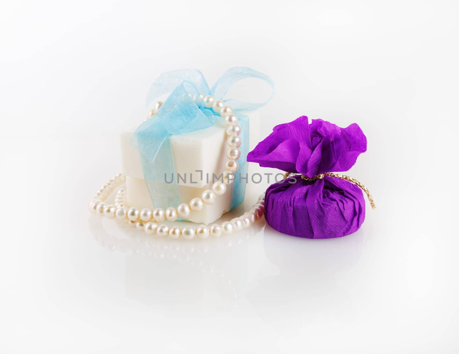 Conceptual festive still life. Gift box, soap and a pearl necklace.