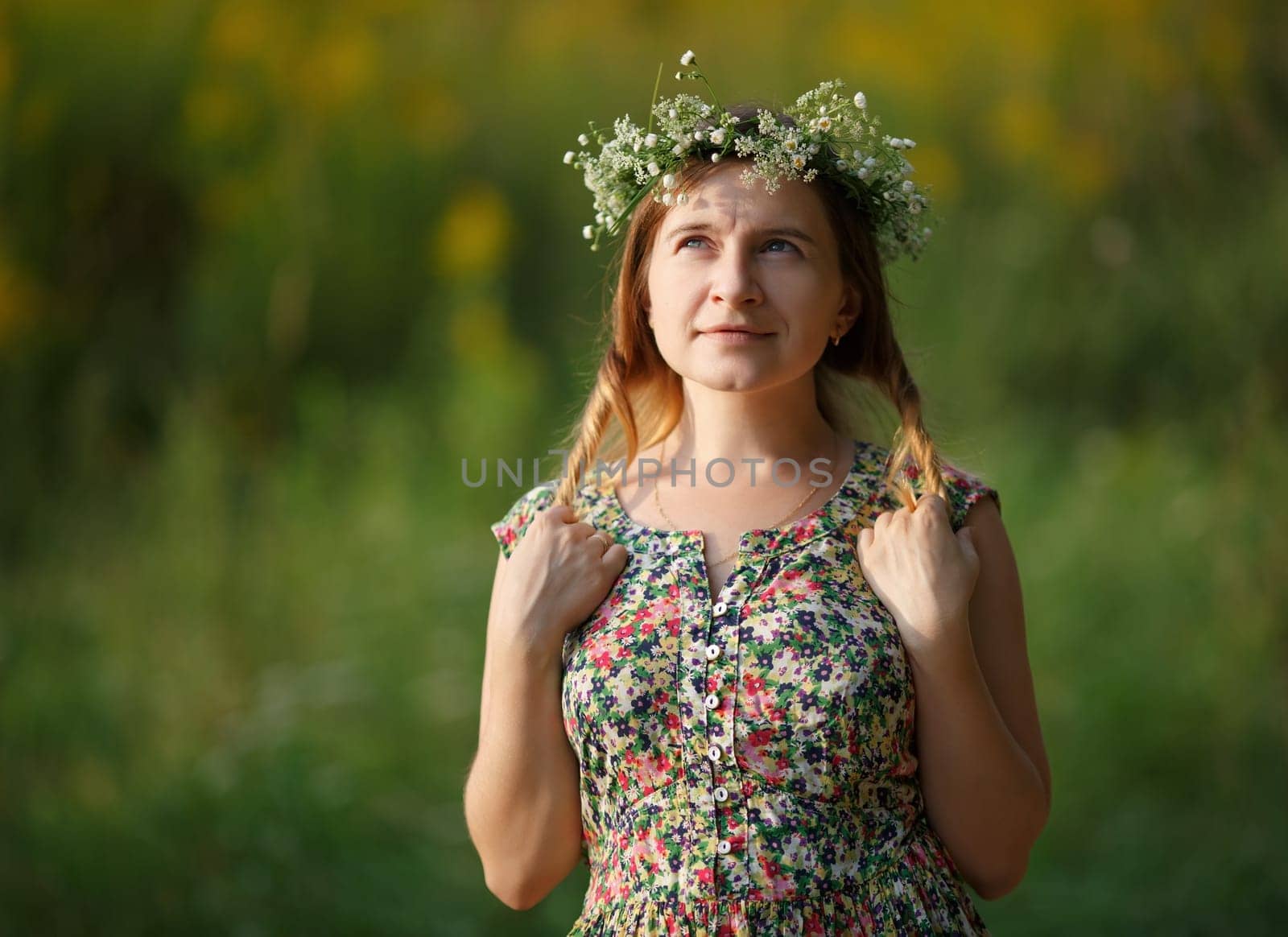 Young woman with wreath holding his hair and looking up. Sunset light. Shallow depth of field. Focus on model.