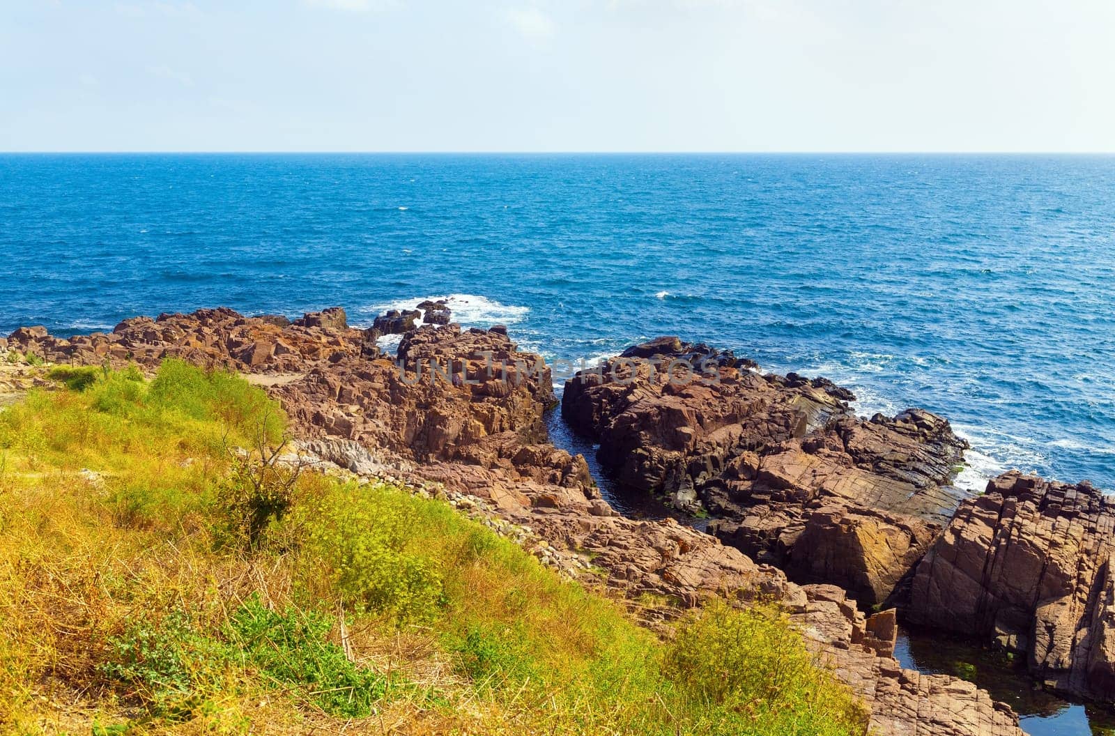 Beautiful seascape. Sea coast in a hot summer day. Rocky coast with bright blue sea water and large stones.