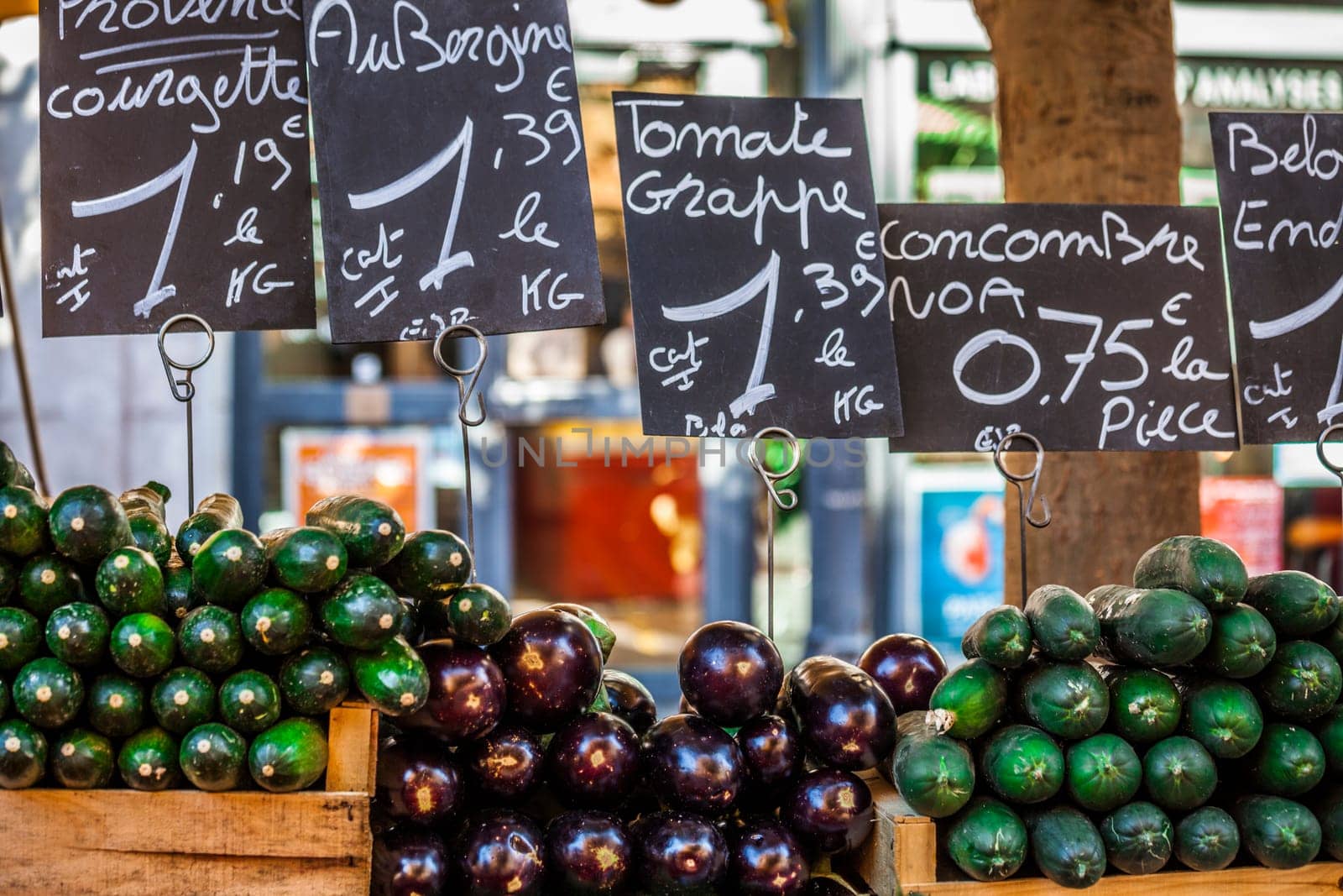 Market table filled with eggplants, zucchini and cucumber at french typical market