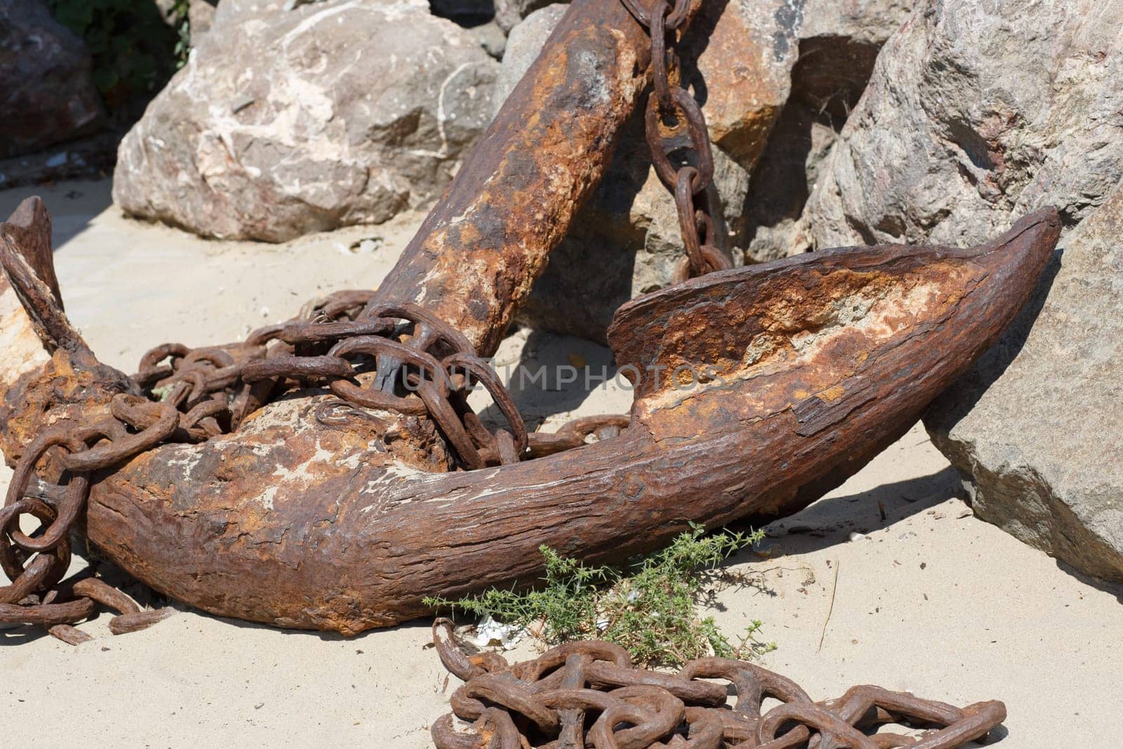 A large fragment of old weathered rusty ship anchor