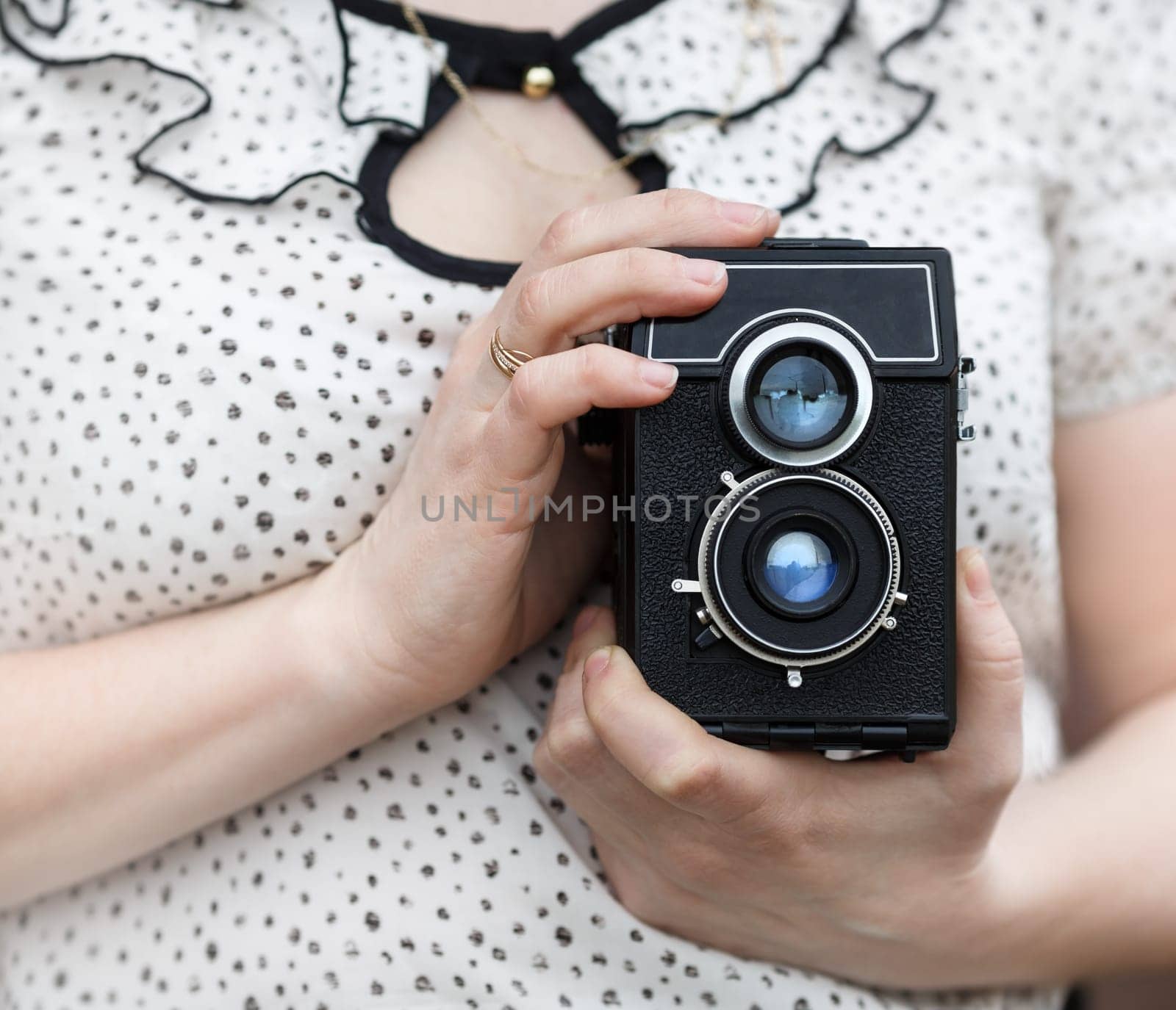 Old vintage camera in retro style in female hands. Shallow depth of field. Selective focus on camera.