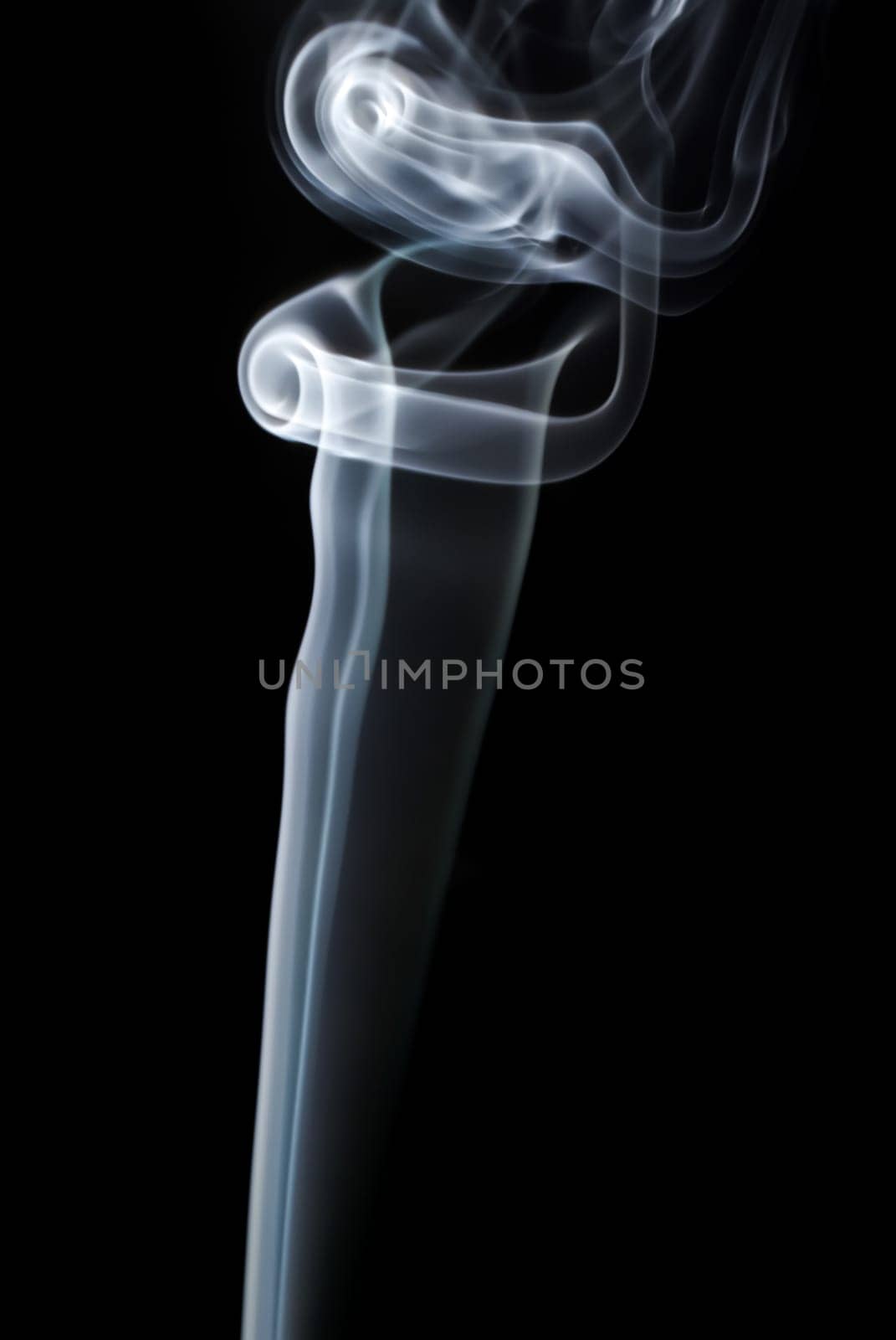 Photo of abstract light smoke swirls on black background. Vertical shot.