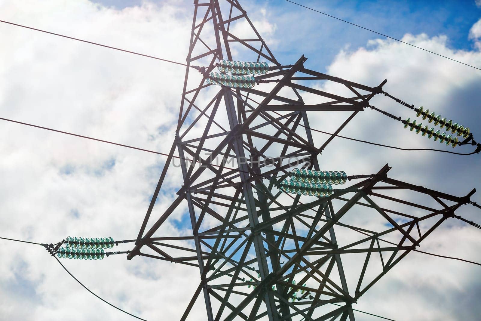 Close-up of high voltage tower. Electricity pylon against cloudy sky background.