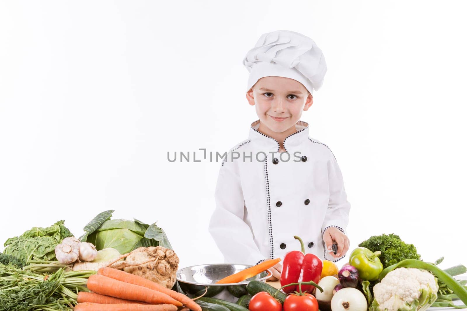 One little boy as chef cook making salad, cooking with vegetables. Isolated on white.