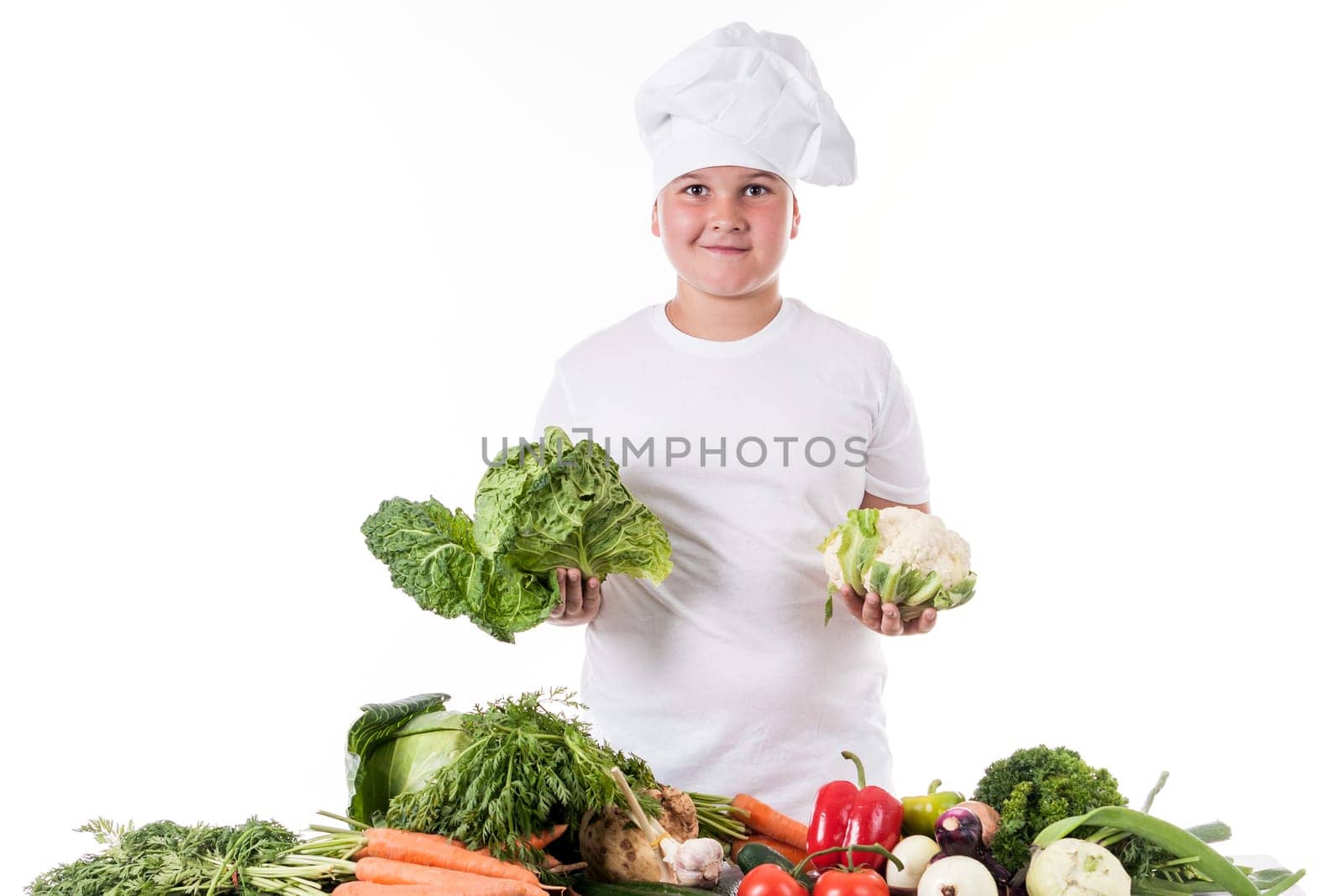 One little boy as chef cook making salad, cooking with vegetables. Isolated on white.