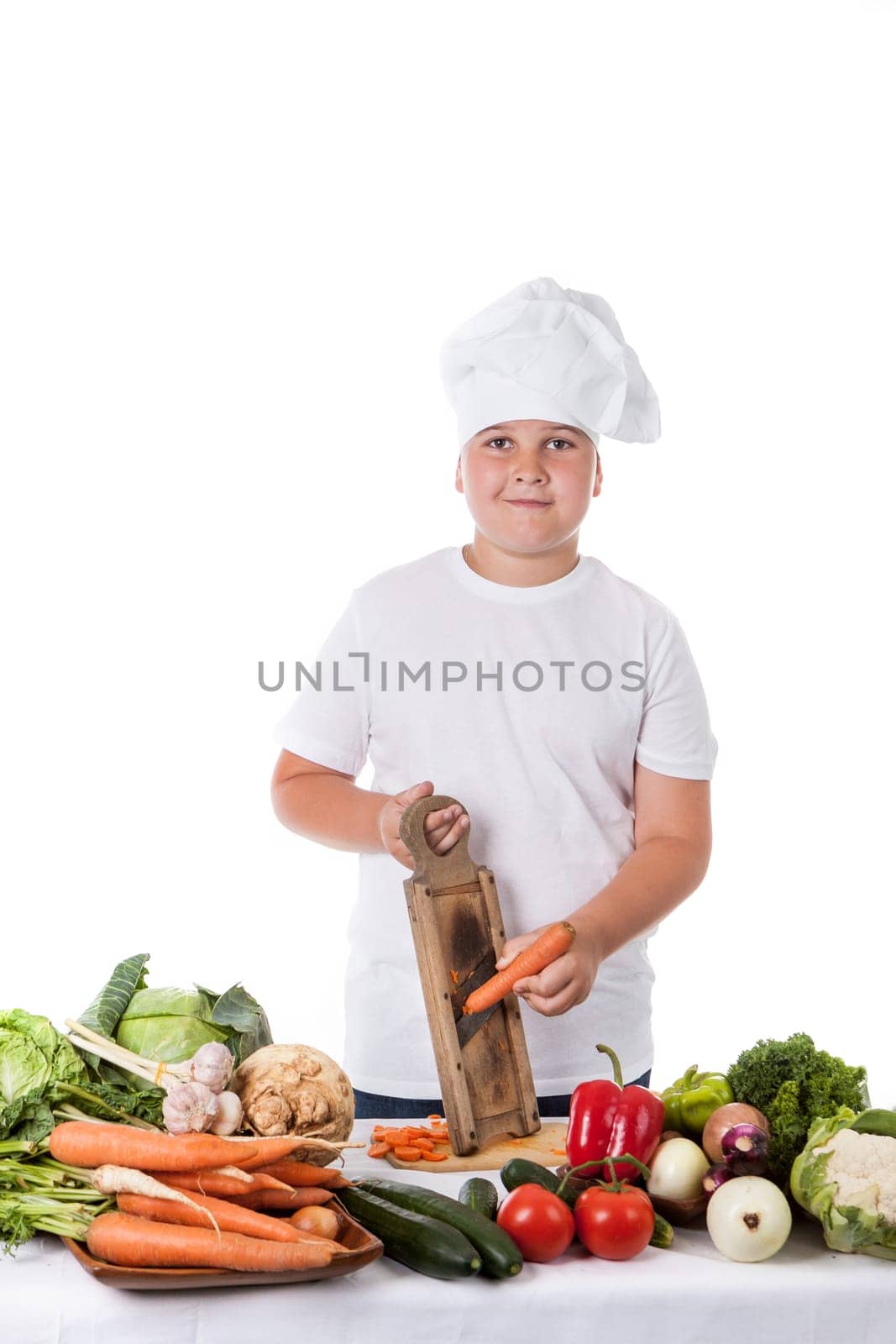 One little boy as chef cook making salad, cooking with vegetables. Isolated on white.