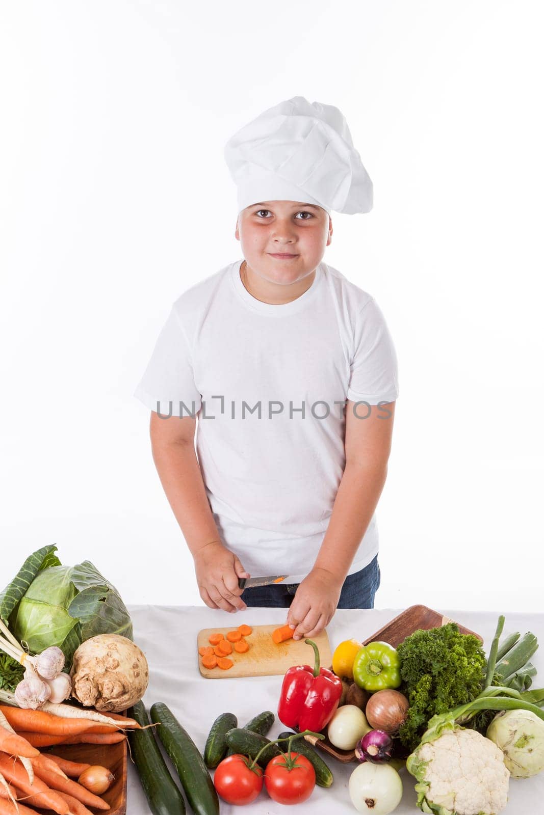 One little boy as chef cook making salad, cooking with vegetables. Isolated on white.