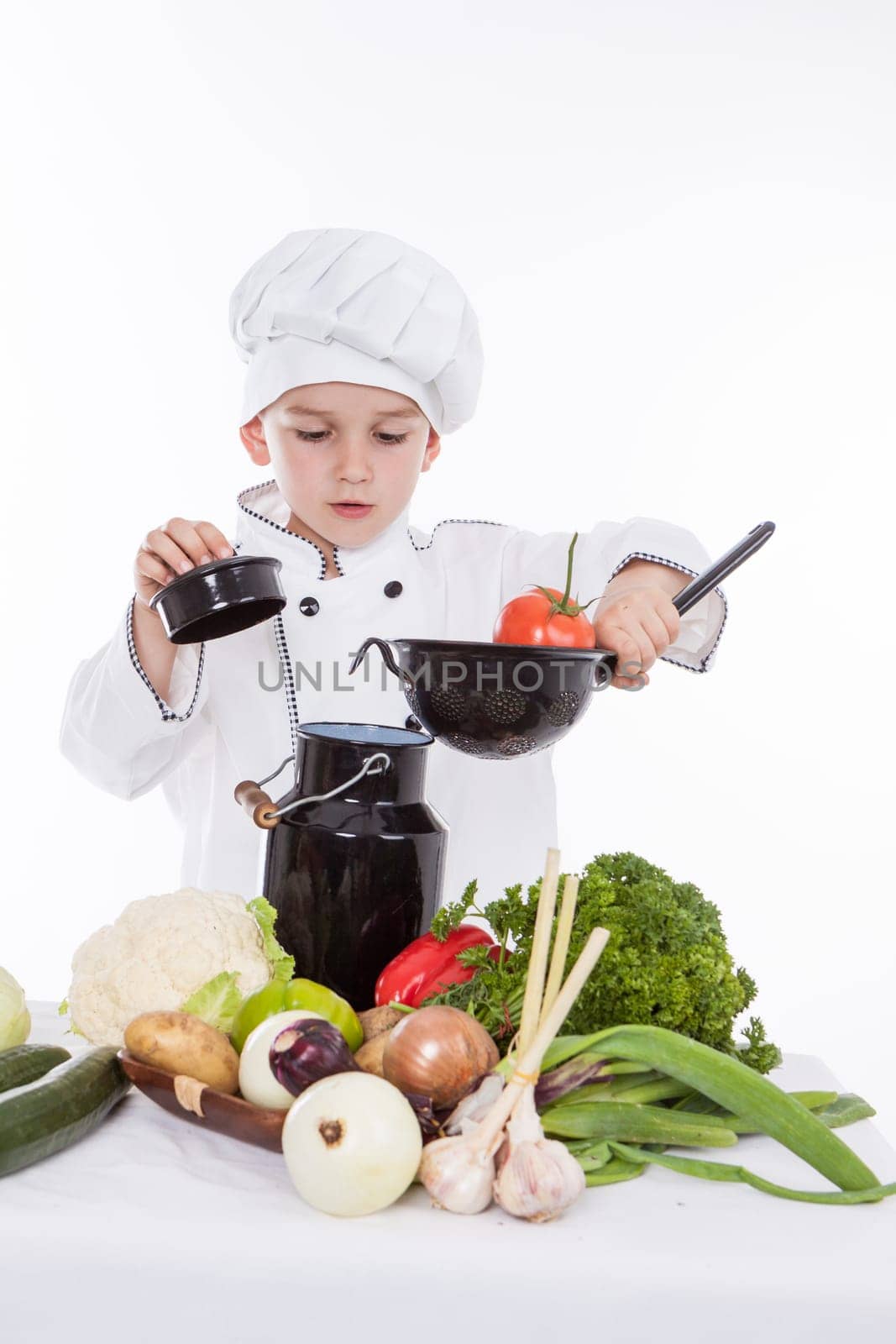 One little boy as chef cook making salad, cooking with vegetables. Isolated on white.